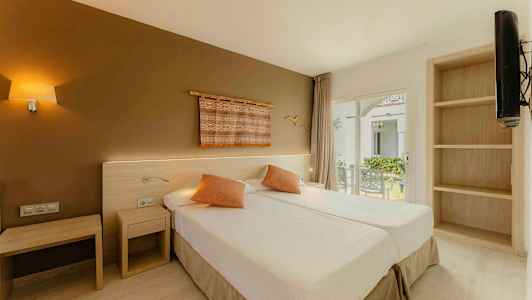 Et hotellrom med to enkeltsenger, dekorative puter og en vegg med kunst. Vindu med utsikt over en hage. (AI-generert tekst)