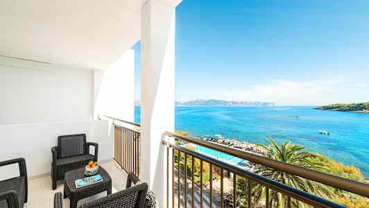 En balkong med sittemøbler som vender mot havet. (AI-generert tekst)