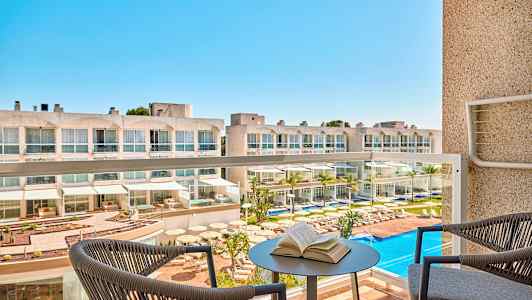 Hotell med bassengområde sett fra en balkong. (AI-generert tekst)