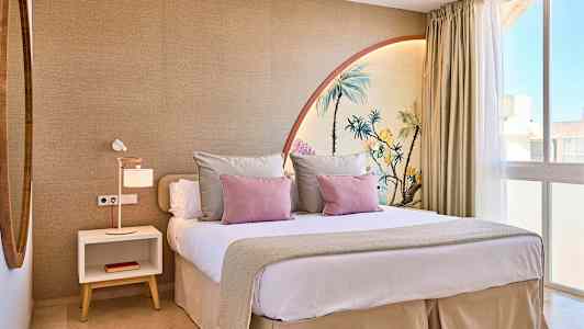 Et moderne soverom med en stor seng, dekorert med pynteputer og en veggmaleri som forestiller palmer. (AI-generert tekst)