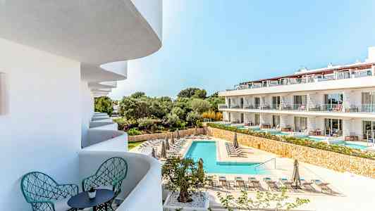 Bildet viser et ferieanlegg med basseng og solsenger, samt balkonger med sitteplasser. (AI-generert tekst)