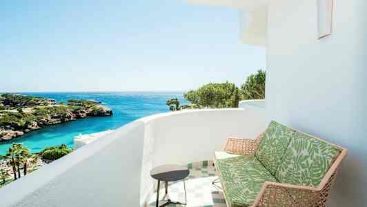 En balkong med utsikt over havet, med grønne planter og klipper. (AI-generert tekst)