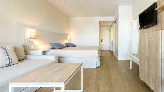 Et hotellrom med seng, sofa og TV. (AI-generert tekst)