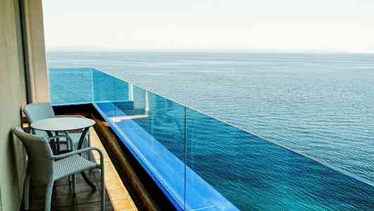 En balkong med to stoler og et bord som vender mot havet. (AI-generert tekst)