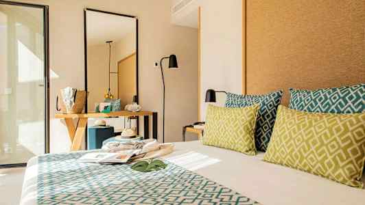 Hotellrom med moderne innredning, seng med dekorative puter, speil og skrivebord. (AI-generert tekst)