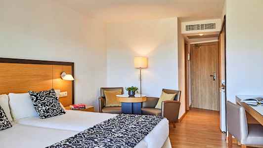 Hotellrom med to enkeltsenger, sittegruppe og skrivebord. (AI-generert tekst)