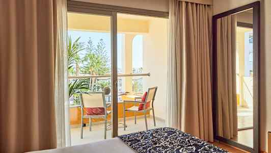 Hotellrom med balkong og utsikt over vegetasjon. (AI-generert tekst)