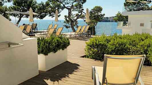 Solstoler og parasoller på en terrasse med havutsikt. (AI-generert tekst)