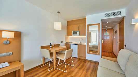 Et hotellrom med kjøkkenkrok og spisebord. (AI-generert tekst)