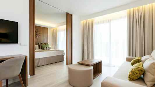 Lyst og innbydende hotellrom med separat sovedel og stueområde. (AI-generert tekst)