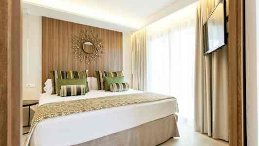 Moderne hotellrom med dobbeltseng, veggdekorasjon og TV. (AI-generert tekst)