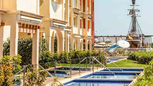 En bygning med bassenger foran, og i bakgrunnen er et sjørøverskip. (AI-generert tekst)