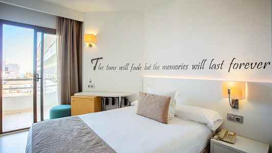 Hotellrom med en dobbeltseng, skrivebord og balkongdør. (AI-generert tekst)