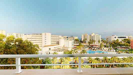 Hotell og bassengområde sett fra en balkong. (AI-generert tekst)