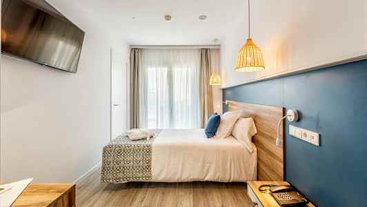 Et hotellrom med en dobbeltseng, en blå veggpanel, en TV på veggen og naturlige treoverflater. (AI-generert tekst)