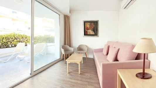 Sofa med rosa trekk, stuebord, to stoler og vindu med utsikt mot terrassen. (AI-generert tekst)