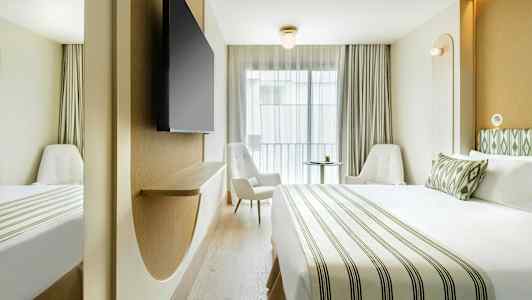 Et moderne hotellrom med en stor seng, to stoler og en veggmontert TV. (AI-generert tekst)