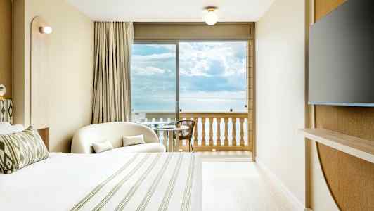 Et hotellrom med havutsikt fra balkongen. Et stort vindu vender mot havet. (AI-generert tekst)