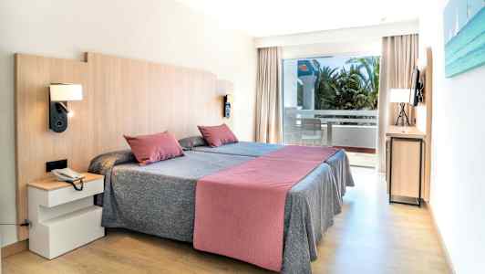 Et hotellrom med to enkeltsenger, en balkong og moderne innredning. (AI-generert tekst)