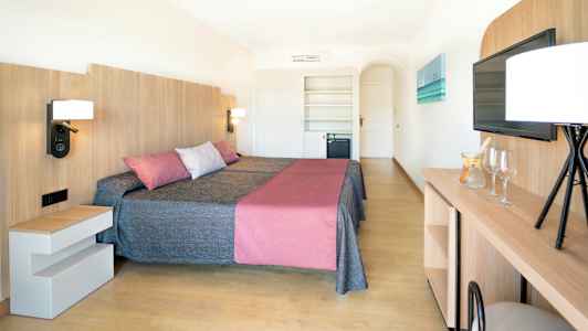 Et hotellrom med to senger, en moderne innredning med tredetaljer, og en TV på veggen. (AI-generert tekst)