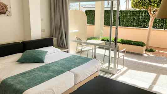 Moderne innredet hotellrom med seng og utsikt mot en privat terrasse. (AI-generert tekst)