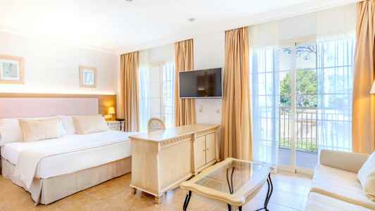 Hotellrom med dobbeltseng, TV, skrivebord og sofa. Balkong med utsikt. (AI-generert tekst)