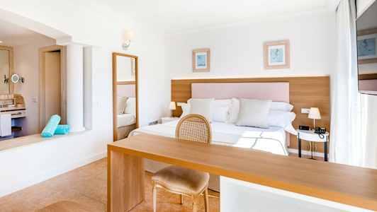 Lyst og romslig hotellrom med dobbeltseng, skrivebord og stol. (AI-generert tekst)