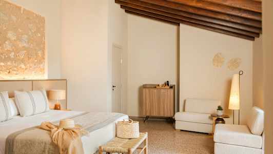 Et innredet hotellrom med en seng, sittemøbler og et skap. Rommet har en varm, moderne stil med beige og naturlige trematerialer. (AI-generert tekst)