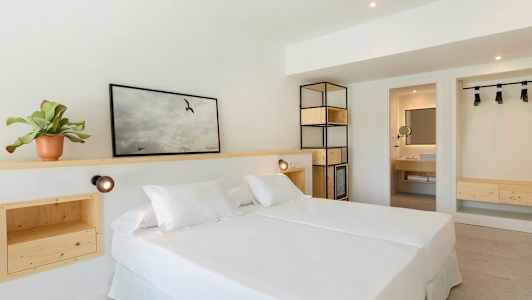 Et lyst hotellrom med en dobbeltseng og innredning av tre. (AI-generert tekst)