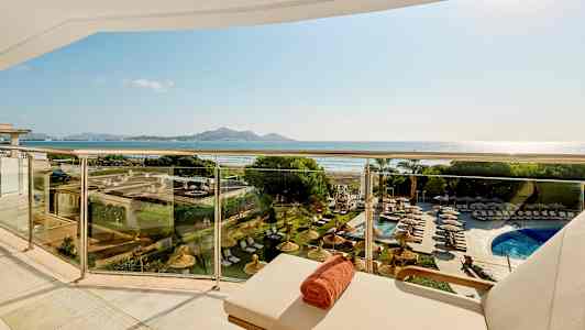 Utsikt fra balkong med solsenger og basseng, med strand og fjell i bakgrunnen. (AI-generert tekst)