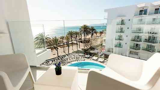 Utsikt fra en balkong mot et basseng, palmer og havet. (AI-generert tekst)