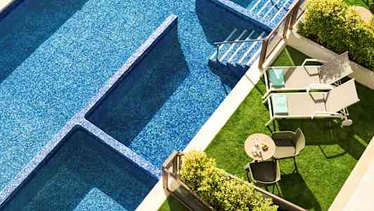 Bilde av et svømmebasseng med blå mosaikk, to solsenger og et bord med stoler på en grøntområde. (AI-generert tekst)