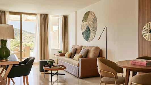 Stue med sofa, sofabord, spisebord og stoler samt utsikt gjennom store vinduer mot natur. (AI-generert tekst)