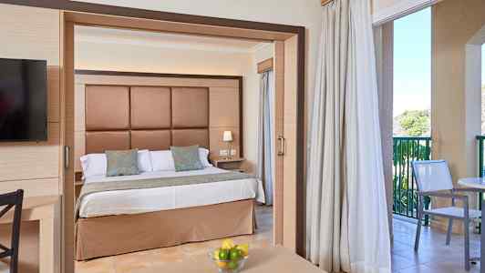 Hotellrom med dobbeltseng, sitteplasser og balkong. (AI-generert tekst)