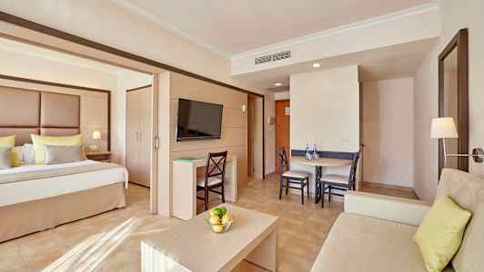 Et hotellrom med seng, sittegruppe og spisebord. (AI-generert tekst)