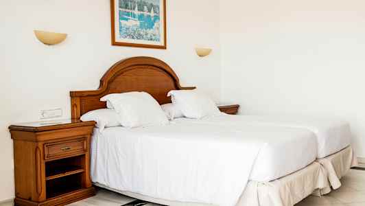 Et soverom med to enkeltsenger, en tresengegavl og et nattbord. (AI-generert tekst)