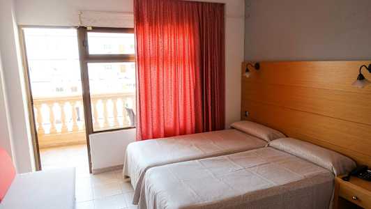 Hotellrom med to enkeltsenger, rød gardin og balkong. (AI-generert tekst)