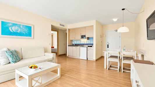 Stue med sofa, sofabord, spisebord og et tekjøkken. (AI-generert tekst)