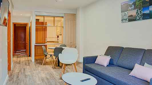 Et stue med en sofa, et salongbord og en spiseplass nær et kjøkken. (AI-generert tekst)