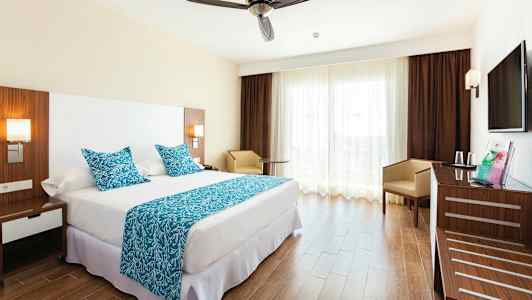 Hotellrom med en dobbeltseng, blå tekstiler og en moderne innredning. (AI-generert tekst)