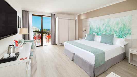 Moderne hotellrom med dobbeltseng, skrivebord, TV og balkong med utsikt. (AI-generert tekst)