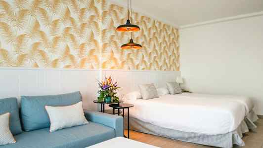 Hotellrom med blå sofa, dobbeltseng og dekorativt tapet. (AI-generert tekst)