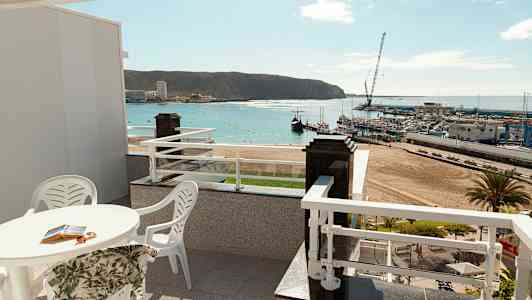 Terrasse med utsikt over en strand og en havn. (AI-generert tekst)