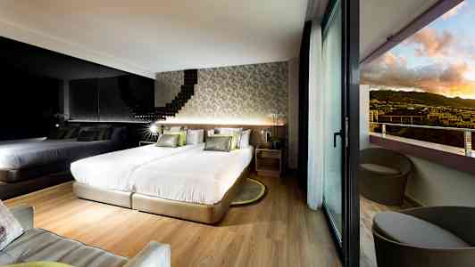 Moderne hotellrom med to senger, en speilvegg og balkong med utsikt over landskapet. (AI-generert tekst)