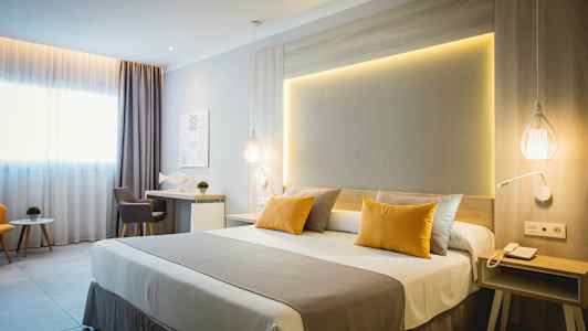 Et moderne hotellrom med dobbeltseng, skrivebord og sittegruppe. (AI-generert tekst)