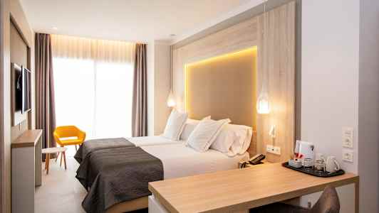 Moderne hotellrom med to enkeltsenger, skrivebord og gul stol. (AI-generert tekst)