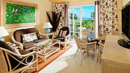 En stue med rottingmøbler, et glassbord og et fargerikt bilde på veggen. (AI-generert tekst)