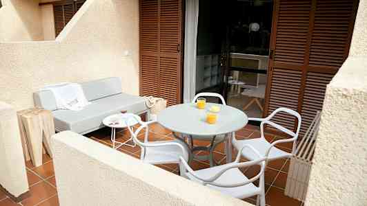 En terrasse med en grå sofa, et rundt bord og stoler. (AI-generert tekst)