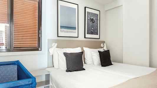 Et hotellrom med en dobbeltseng, to puter og dekorasjoner på veggen. (AI-generert tekst)