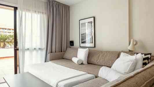 Et oppholdsrom med en sovesofa, et salongbord og en utgang til balkongen. (AI-generert tekst)